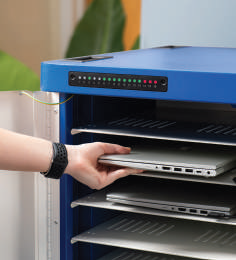 User placing a laptop in the ChargeLite demonstrating the front charge status lights