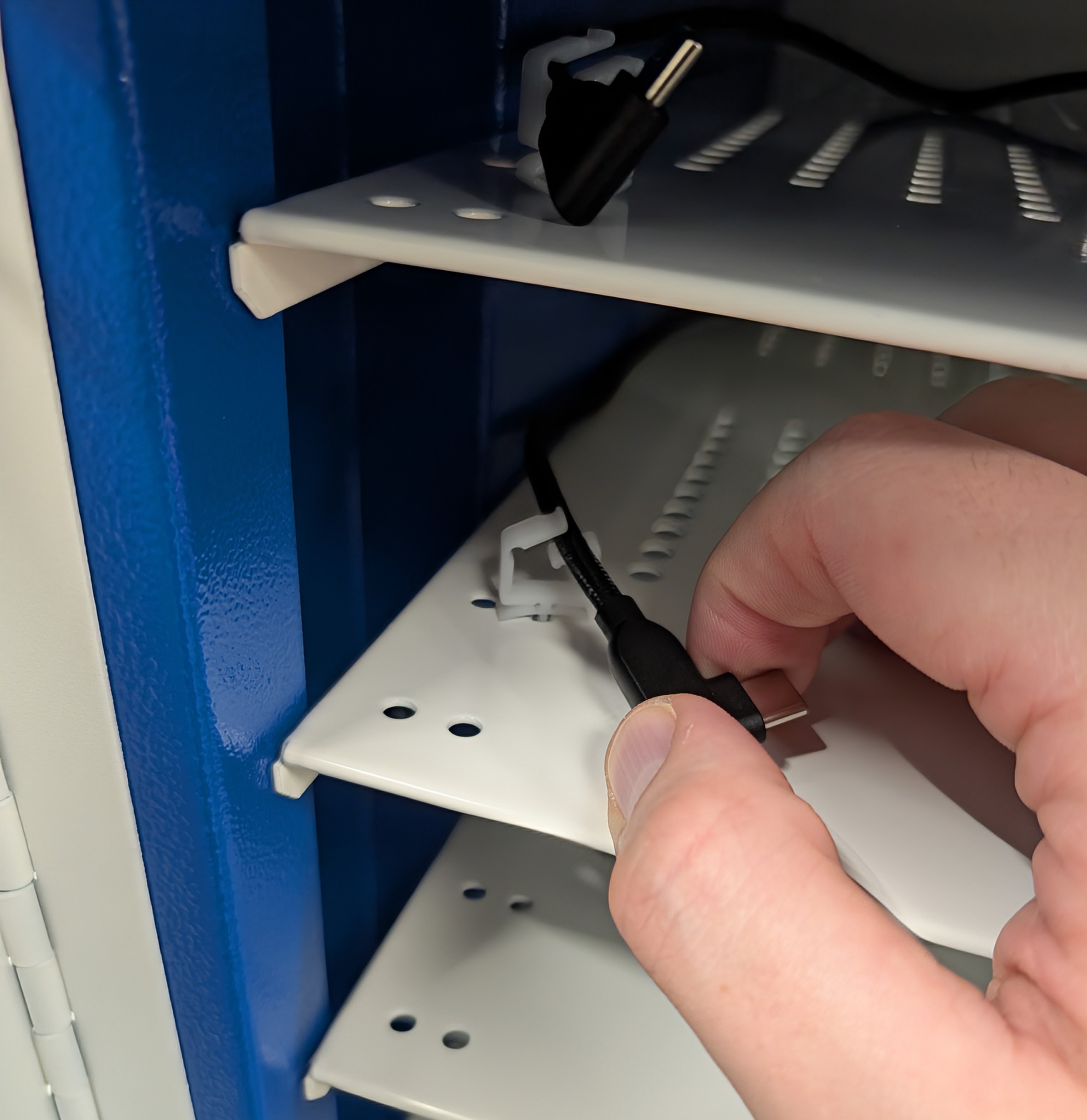 Threading USB-C charging leads through white clips installed on the trolley shelves